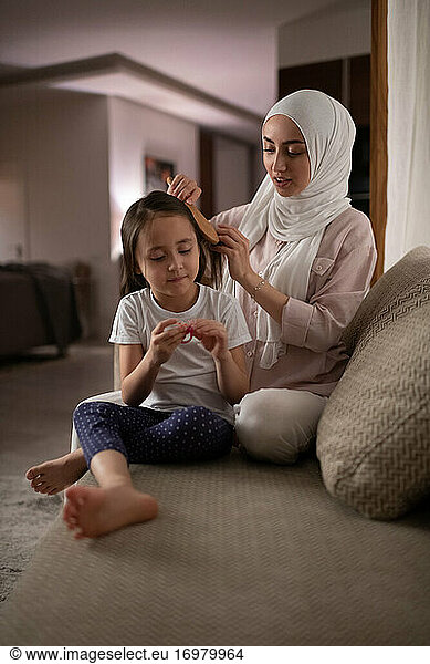 Muslimische Mutter kämmt das Haar ihrer Tochter