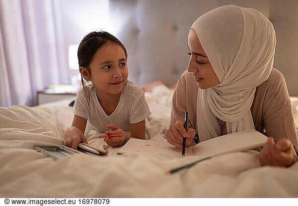 Muslimische Mutter und Tochter zeichnen auf dem Bett