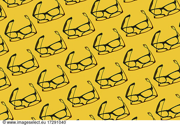 Muster von Reihen von einfachen klassischen Brillen flach auf gelbem Hintergrund gelegt