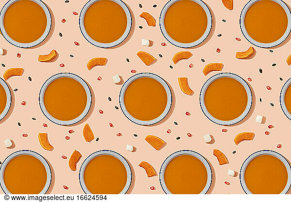 Muster von Schalen mit Kürbissuppe  umgeben von Kürbiskernen  Granatapfelkernen und Stücken von Käse und Kürbis