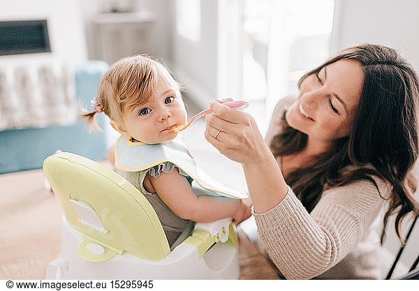Mutter füttert ihre Tochter im Kindersitz  Porträt