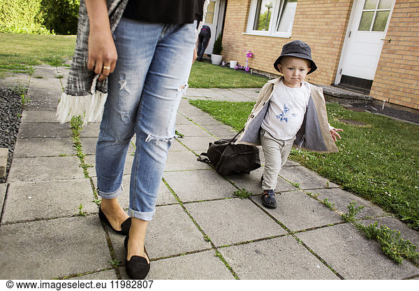 Mutter geht mit Sohn (18-23 Monate) auf dem Gehweg spazieren