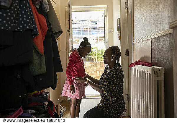 Mutter hilft Tochter mit Jacke an Haustür