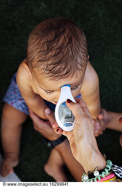 Mutter prüft Temperatur des Babys mit Thermometer