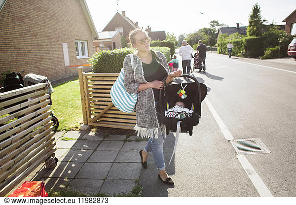 Mutter trägt ihren Sohn (0-1 Monate) in einem tragbaren Autositz