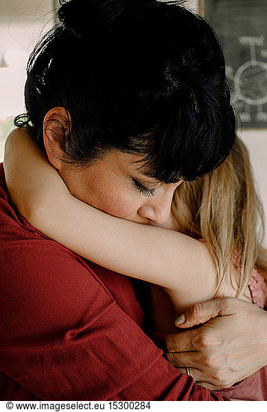 Mutter umarmt  während sie ihre Tochter zu Hause tröstet