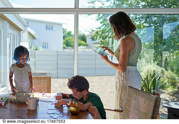 Mutter und Kinder arbeiten und spielen am Esstisch