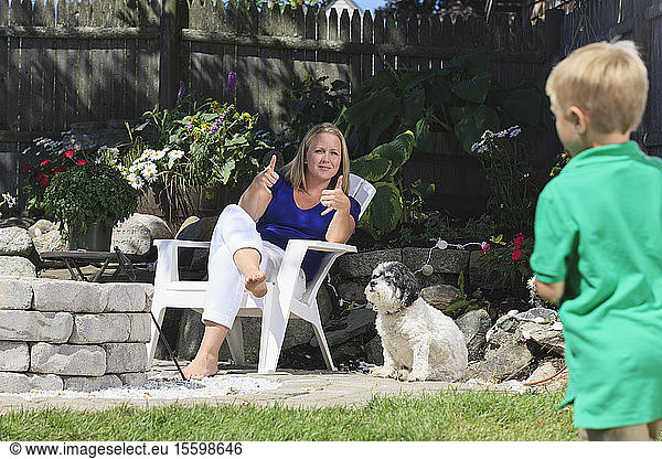Mutter und Sohn mit Hörbehinderung spielen Fußball und gebärden play in amerikanischer Zeichensprache im Hinterhof
