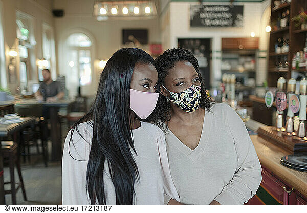 Mutter und Tochter mit Gesichtsmasken in der Kneipe