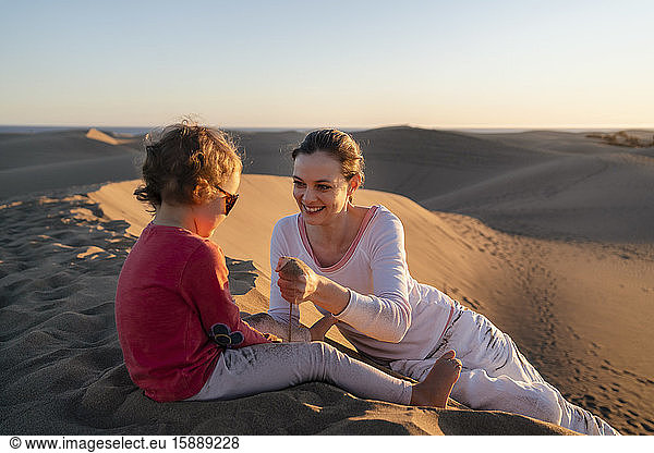 Mutter und Tochter spielen bei Sonnenuntergang mit Sand in den Dünen  Gran Canaria  Spanien