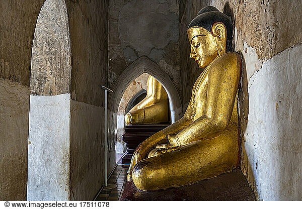 Myanmar  Mandalay Region  Bagan  Gold colored statue of meditating Buddha inside Manuha Temple