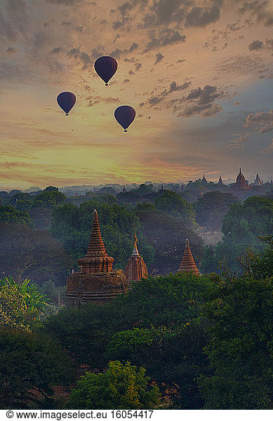 Myanmar  Mandalay Region  Bagan  Silhouettes of hot air balloons flying over ancient temples at moody dawn