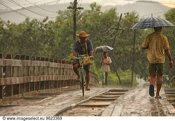 Myanmar  people on footbridge in monsoon rainfall