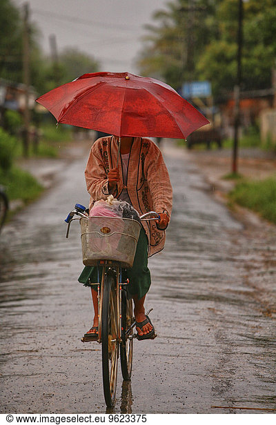 Myanmar  woman on bike in monsoon rainfall
