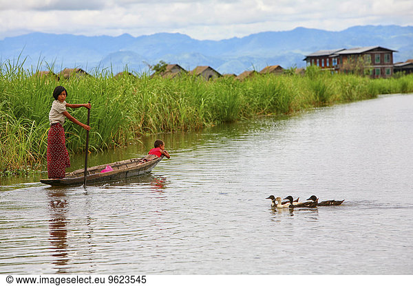 Myanmar  woman with child on boat and ducks on Inle Lake