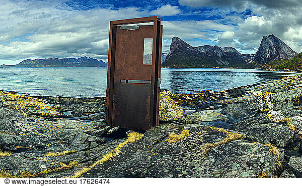 Mysterious door standing on rocky shore of Senja island