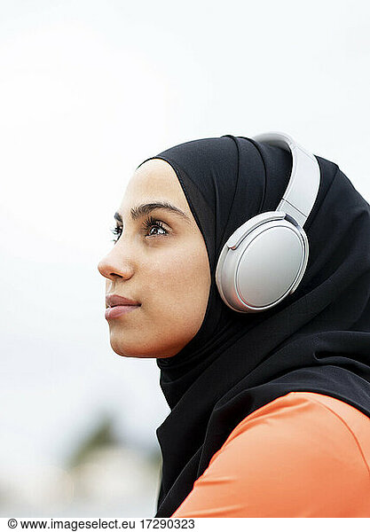 Nachdenkliche arabische Frau mit Kopfhörern im Freien