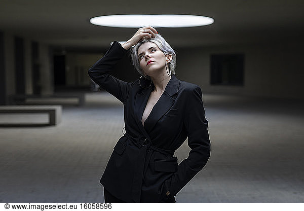 Nachdenkliche Geschäftsfrau im eleganten schwarzen Anzug im Büro
