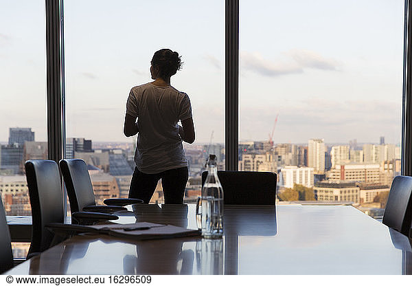 Nachdenkliche Geschäftsfrau schaut aus dem Fenster eines Hochhausbüros