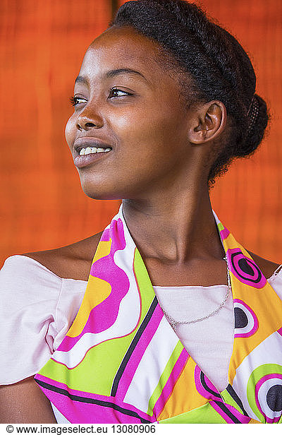 Nachdenkliche junge Afrikanerin schaut weg gegen orangefarbene Wand
