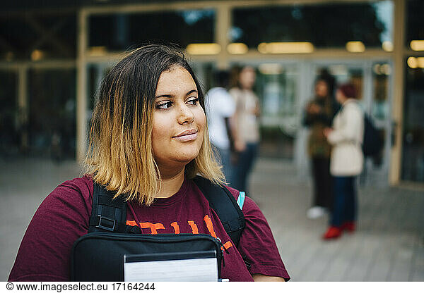 Nachdenkliche Studentin beim Wegschauen auf dem Campus