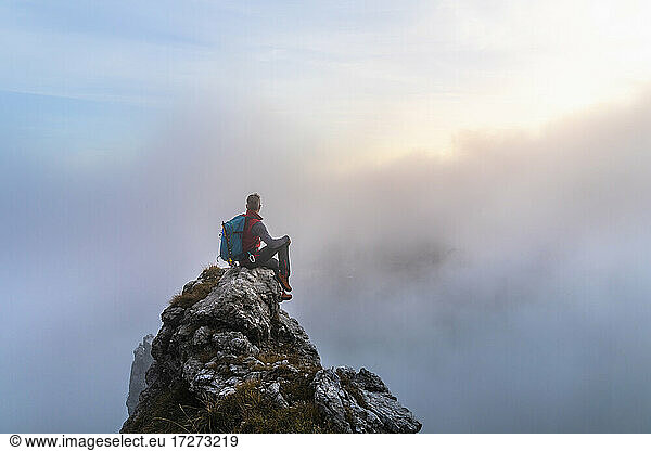 Nachdenklicher männlicher Wanderer bei Sonnenaufgang auf einem Berggipfel in den Bergamasker Alpen  Italien