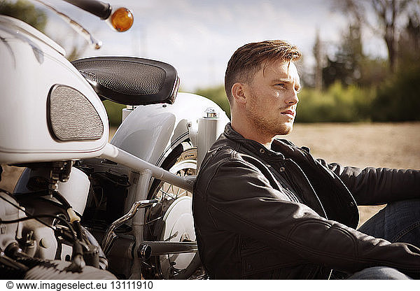 Nachdenklicher Mann lehnt auf Motorrad