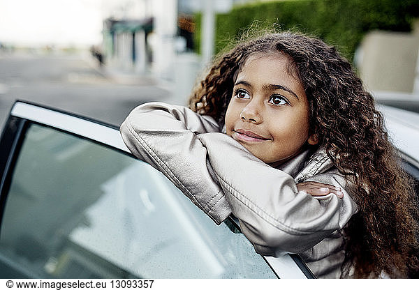 Nachdenkliches Mädchen lehnt an Autotür