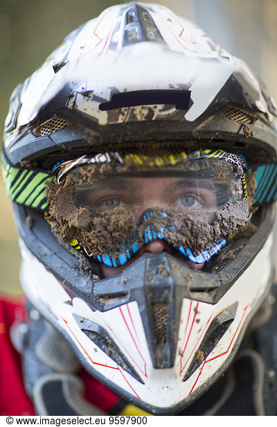 Nahaufnahme des männlichen Motocross-Rennfahrers mit schlammigen Helm und Brille