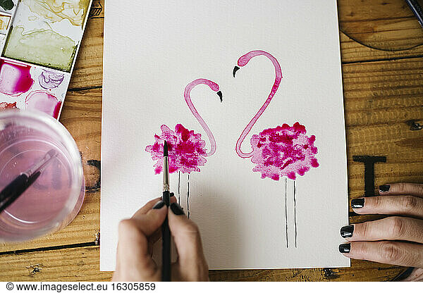 Nahaufnahme einer Frau  die mit der Hand ein Flamingo-Tier auf Papier malt