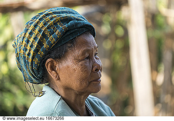 Nahaufnahme einer nachdenklichen älteren birmanischen Frau mit Kopfbedeckung  die wegschaut  Hsipaw  Myanmar