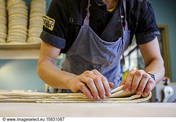 Nahaufnahme eines Bäckers  der Butterteig auf einer Arbeitsplatte faltet