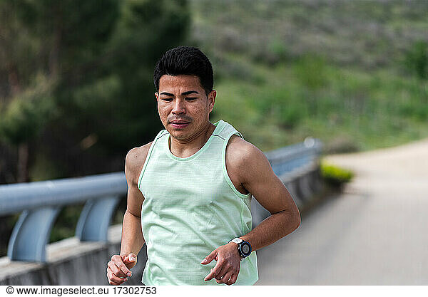Nahaufnahme eines jungen lateinamerikanischen Läufers  der auf einer Brücke läuft.