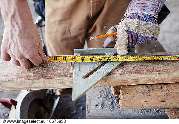 Nahaufnahme eines männlichen Bauarbeiters  der Holz für den Schnitt misst