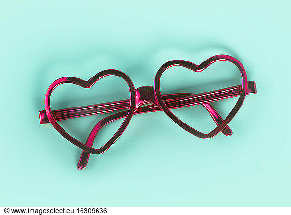 Nahaufnahme eines rosa herzförmigen Brillenglases auf blauem Hintergrund