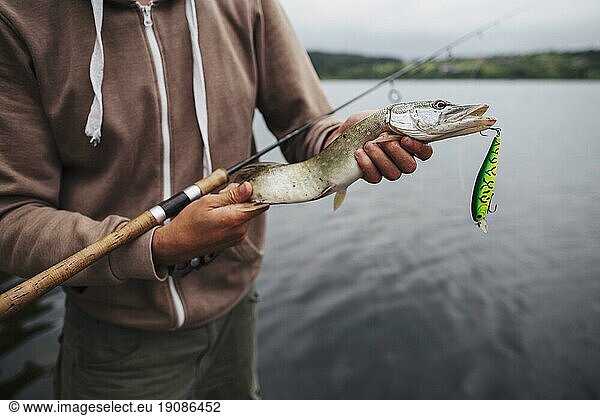 Nahaufnahme Mann hält frisch gefangenen Fisch mit Köder