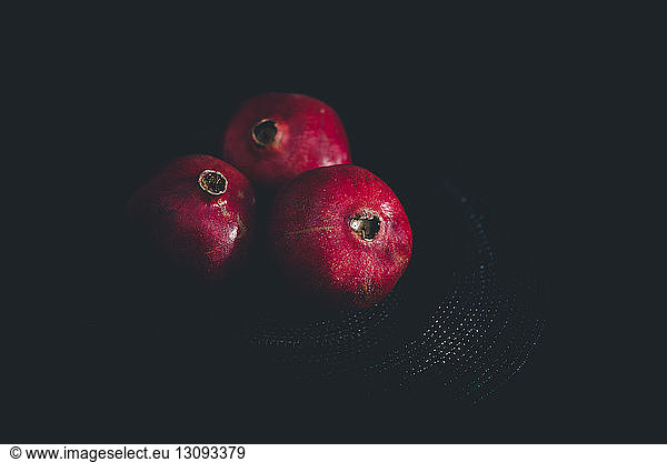 Nahaufnahme von ganzen Granatäpfeln auf Platzdeckchen vor schwarzem Hintergrund