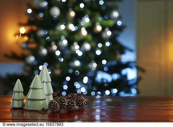 Nahaufnahme von kleinen Weihnachtsbäumen mit Tannenzapfen auf hölzernem Tisch zu Hause