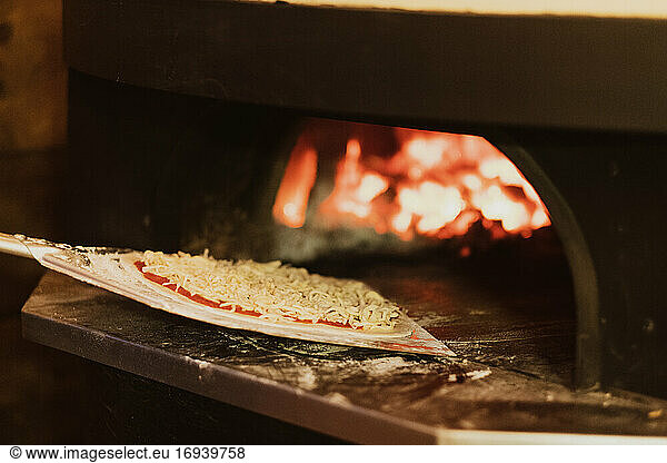 Nahaufnahme von Pizza in einem holzbefeuerten Ofen in einem Restaurant.