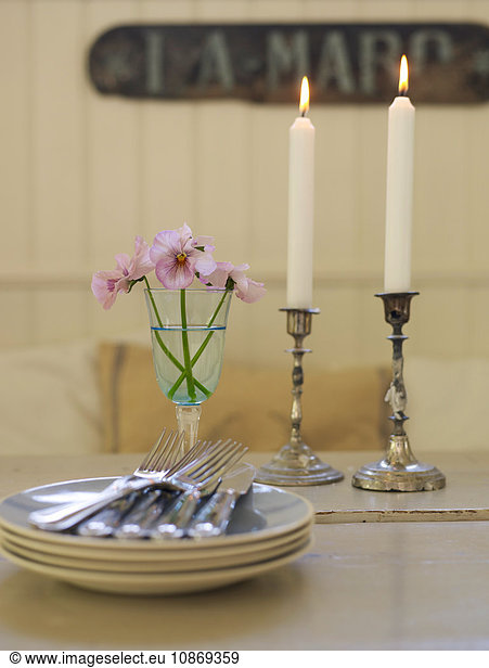 Nahaufnahme von Tellern  Besteck und angezündeten Kerzen auf dem Esstisch