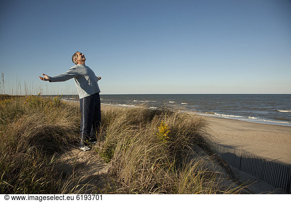 nahe  stehend  Mann  Ozean  Sand  Arme ausbreiten  Arme ausstrecken  Düne  strecken