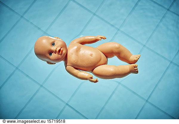 Naked baby doll floating on water in a pool