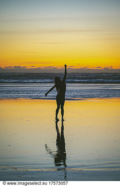 Naked female silhouette posing on the beach at sunset