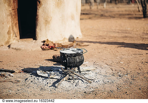 Namibia  Damaraland  iron pot boiling on a small fire in front a hut in a Himba village