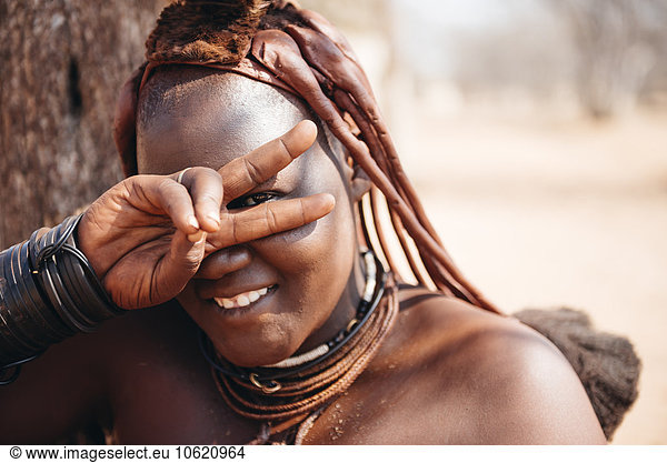 Namibia  Damaraland  portrait of smiling Himba woman making victory sign
