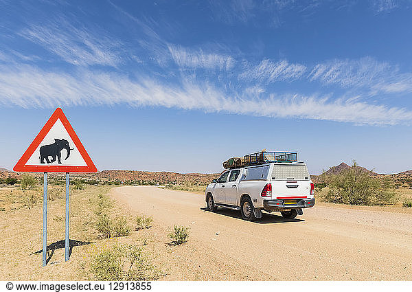 Namibia  Erongo Region  off-road vehicle on sand track  deer crossing sign with elephant