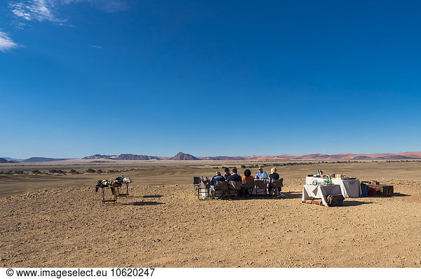 Namibia  Hardap  people sitting at table in desert