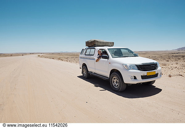 Namibia  Namib Wüste  Swakopmund  Mann auf einem 4x4 Auto mit Zelt auf dem Dach in einer staubigen Straße