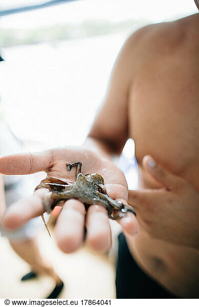 Native American man holding a baby octopus in his hands in Maui