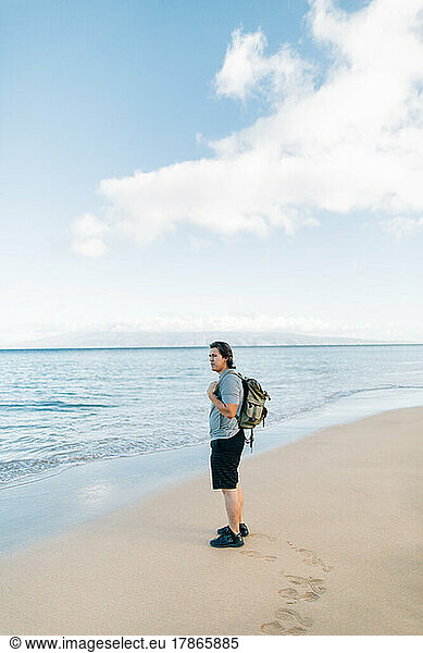 Native American man wearing backpack standing on beach in Maui H